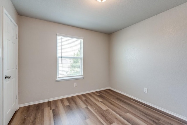 spare room featuring baseboards and wood finished floors