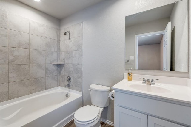 bathroom featuring a textured wall, shower / tub combination, toilet, and vanity