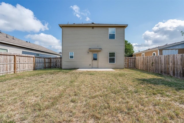 rear view of house with a fenced backyard, a lawn, and a patio