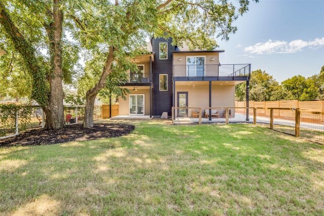 rear view of property with a lawn, a balcony, and a patio