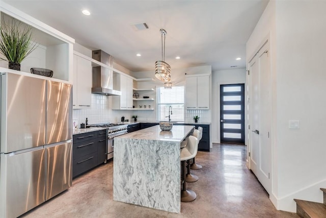 kitchen featuring pendant lighting, open shelves, appliances with stainless steel finishes, white cabinetry, and wall chimney range hood