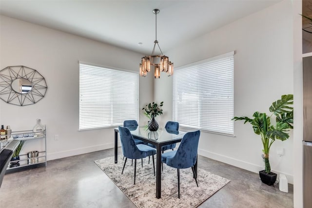 dining room featuring finished concrete flooring, baseboards, and a notable chandelier