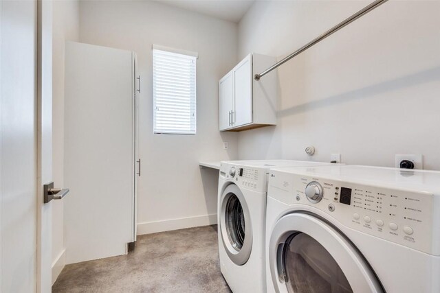 clothes washing area with washing machine and clothes dryer, cabinet space, and baseboards