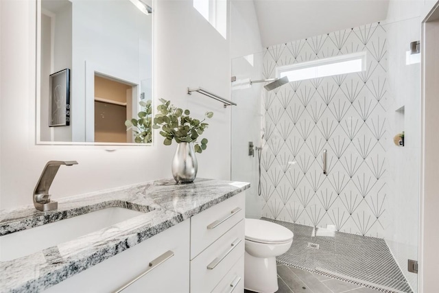 full bathroom with toilet, tiled shower, and vanity