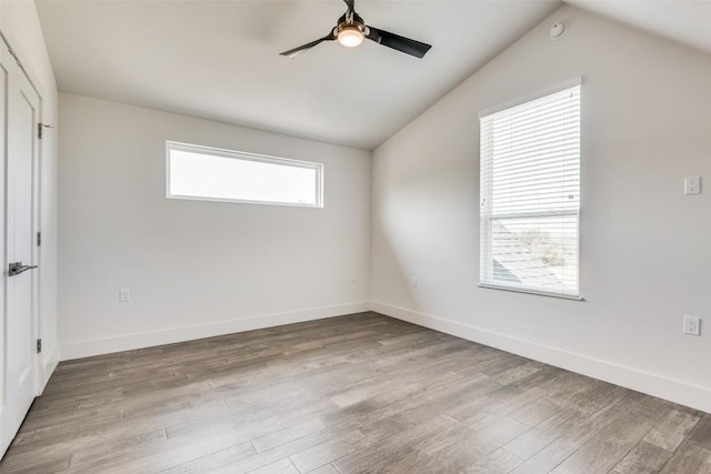 empty room featuring ceiling fan, light wood finished floors, vaulted ceiling, and baseboards