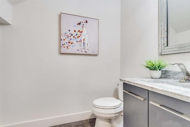 bathroom with toilet, vanity, and baseboards