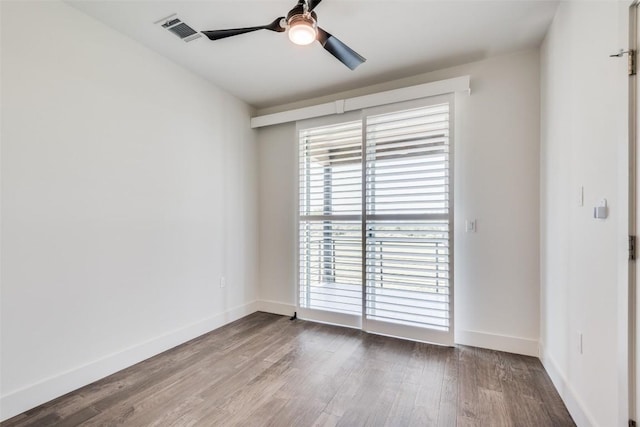 spare room with visible vents, ceiling fan, baseboards, and wood finished floors