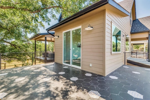 view of side of home with a patio area and roof with shingles