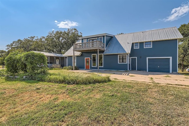 rear view of house with a yard, a balcony, and a garage