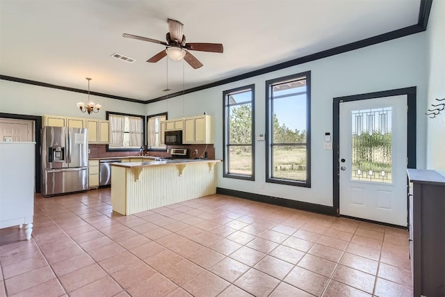 kitchen with pendant lighting, a breakfast bar, light tile patterned floors, ceiling fan with notable chandelier, and appliances with stainless steel finishes