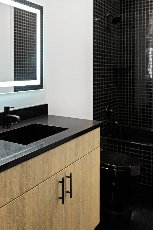 full bathroom featuring tiled shower / bath, vanity, and toilet