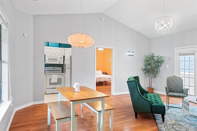 dining space with high vaulted ceiling, a chandelier, and light wood-type flooring