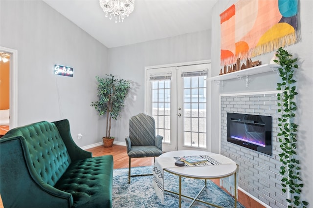 sitting room with hardwood / wood-style floors, a notable chandelier, french doors, and a fireplace