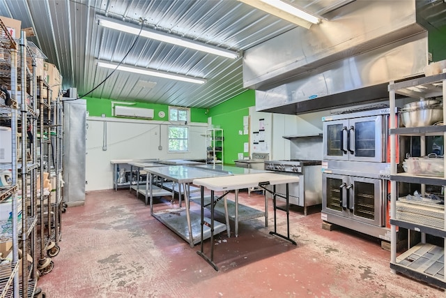 interior space featuring stainless steel range oven, concrete flooring, and a wall mounted air conditioner