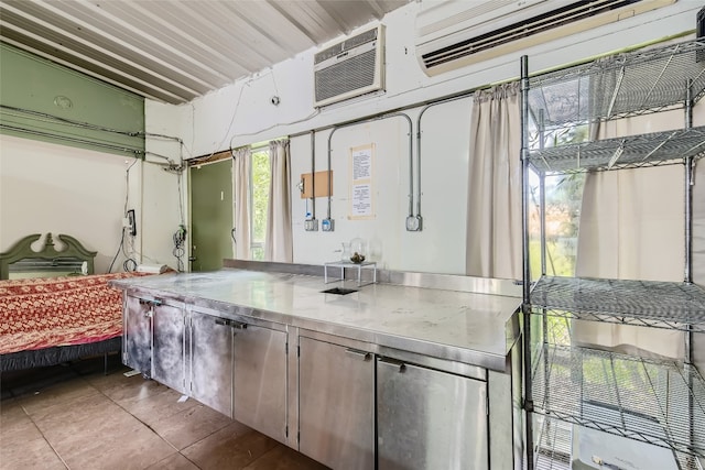 kitchen featuring tile patterned flooring, an AC wall unit, and stainless steel counters