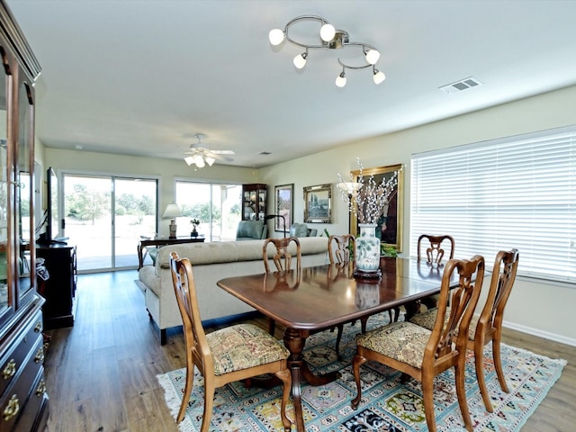 dining area featuring wood-type flooring and ceiling fan with notable chandelier