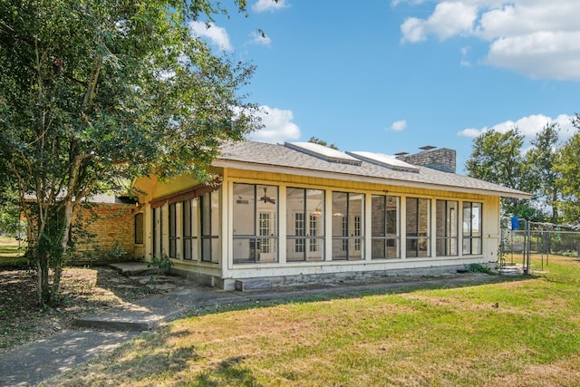 back of house featuring a sunroom and a lawn