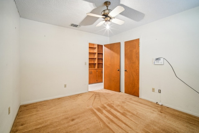 unfurnished bedroom with ceiling fan, a textured ceiling, and light carpet