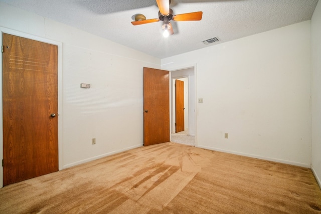 spare room featuring a textured ceiling, ceiling fan, and light colored carpet