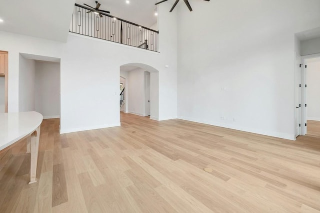 unfurnished living room with a towering ceiling and light hardwood / wood-style floors