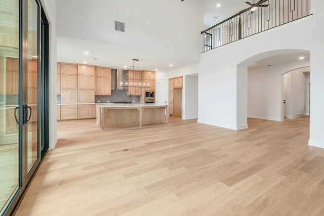 unfurnished living room featuring a towering ceiling and light wood-type flooring