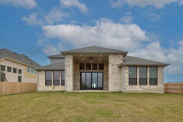 back of property with a yard and ceiling fan