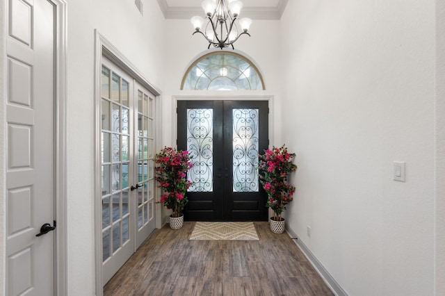 entrance foyer with a notable chandelier, french doors, crown molding, and hardwood / wood-style floors