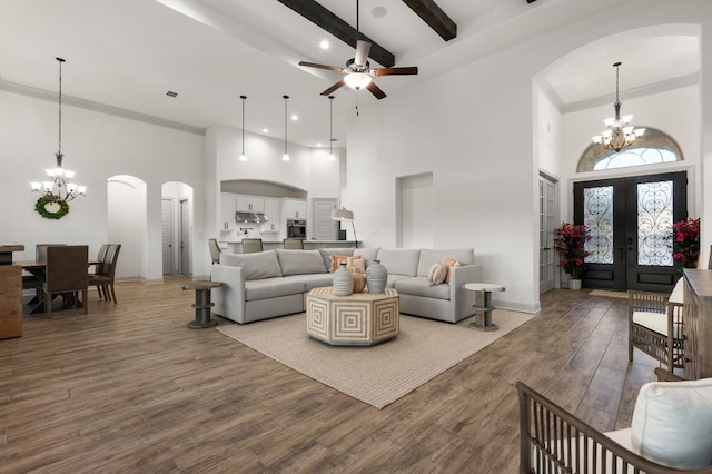 living room with ceiling fan with notable chandelier, a towering ceiling, wood-type flooring, and french doors