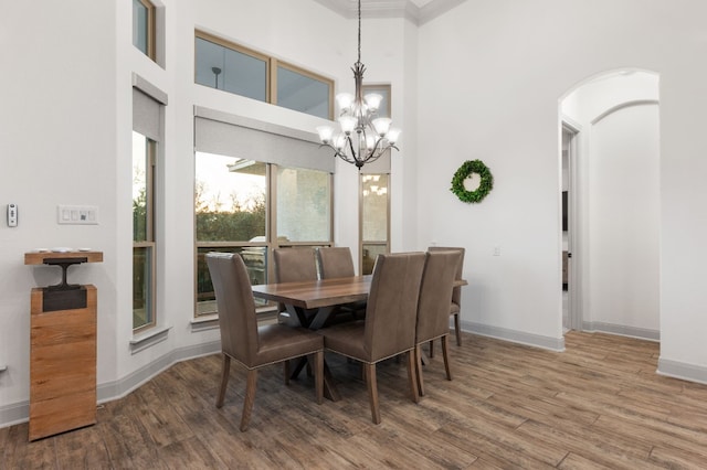 dining space with hardwood / wood-style flooring, a notable chandelier, and a high ceiling