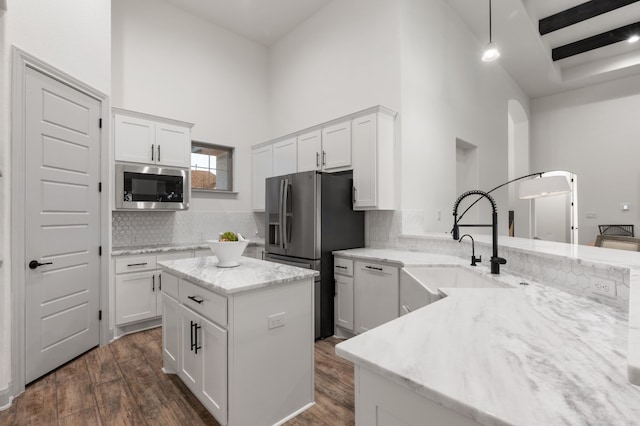 kitchen with appliances with stainless steel finishes, beam ceiling, dark hardwood / wood-style flooring, and tasteful backsplash