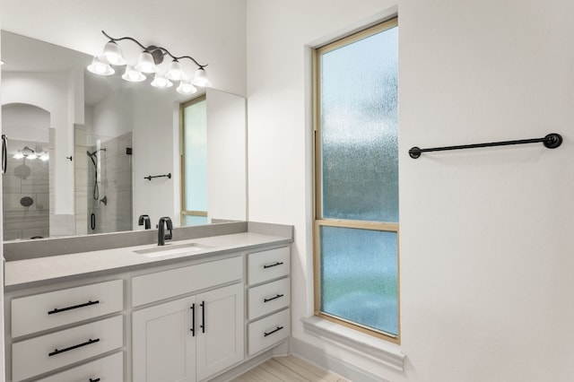 bathroom featuring a shower with door and vanity