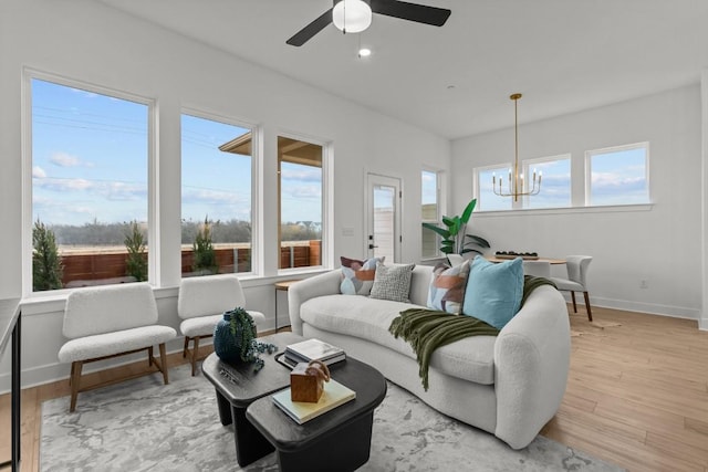 living room with ceiling fan with notable chandelier and light hardwood / wood-style floors