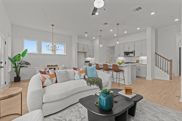 living room with a chandelier, sink, and light hardwood / wood-style flooring