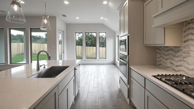 kitchen with dark wood-type flooring, sink, hanging light fixtures, decorative backsplash, and stainless steel appliances