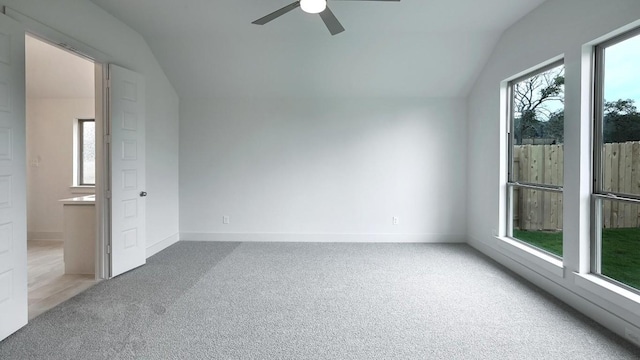 carpeted spare room featuring vaulted ceiling, plenty of natural light, and ceiling fan