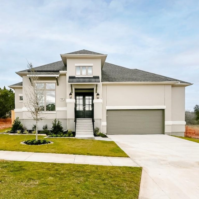 prairie-style house with french doors, a front lawn, and a garage