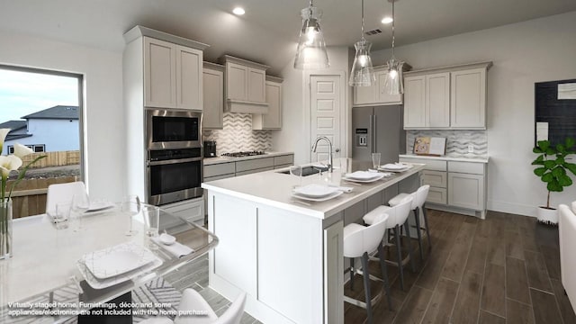 kitchen featuring sink, tasteful backsplash, decorative light fixtures, a kitchen bar, and appliances with stainless steel finishes