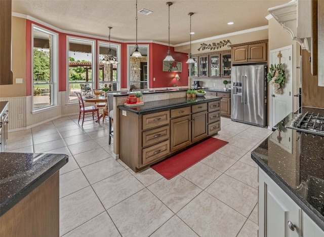 kitchen with hanging light fixtures, a kitchen island, a textured ceiling, ornamental molding, and high end fridge