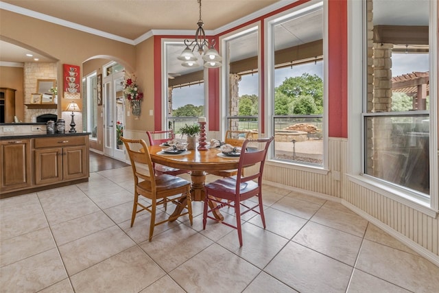 dining room with crown molding, light tile patterned flooring, a fireplace, and a chandelier