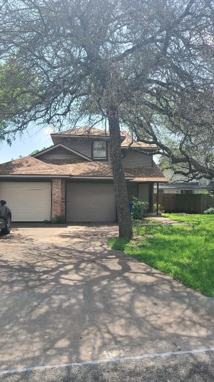 view of front facade with a front lawn, driveway, an attached garage, and fence