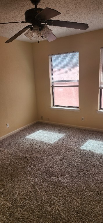 carpeted spare room with a ceiling fan, baseboards, a healthy amount of sunlight, and a textured ceiling