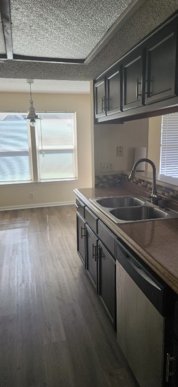 kitchen with dark wood-style flooring, baseboards, a textured ceiling, a sink, and dishwasher