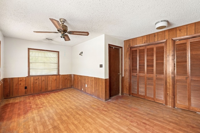 unfurnished room with ceiling fan, light hardwood / wood-style floors, and a textured ceiling