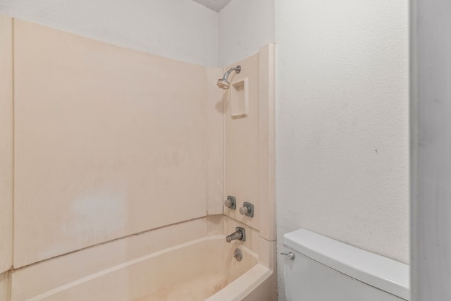 bathroom with a textured wall, toilet, and shower / bath combination