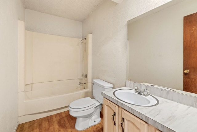 bathroom with a textured ceiling, wood finished floors, toilet, vanity, and shower / bathing tub combination