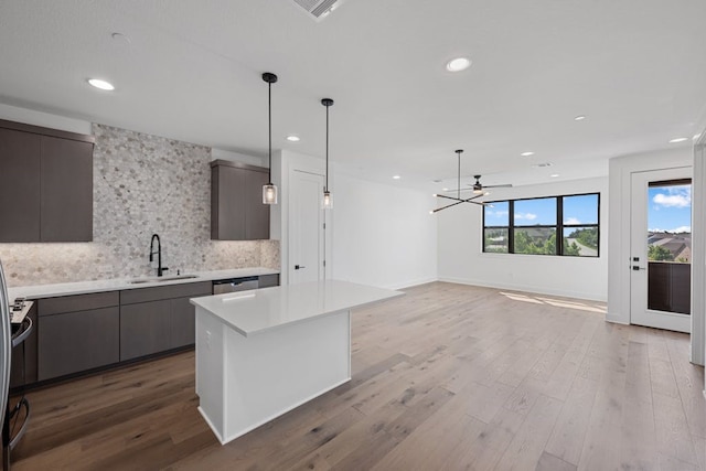 kitchen featuring sink, a center island, hanging light fixtures, backsplash, and hardwood / wood-style floors