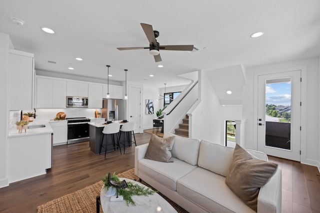 living room featuring ceiling fan and dark hardwood / wood-style flooring