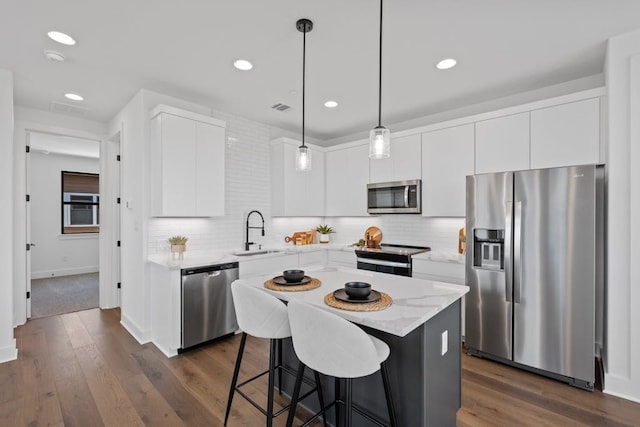 kitchen with white cabinets, sink, hanging light fixtures, dark hardwood / wood-style flooring, and stainless steel appliances