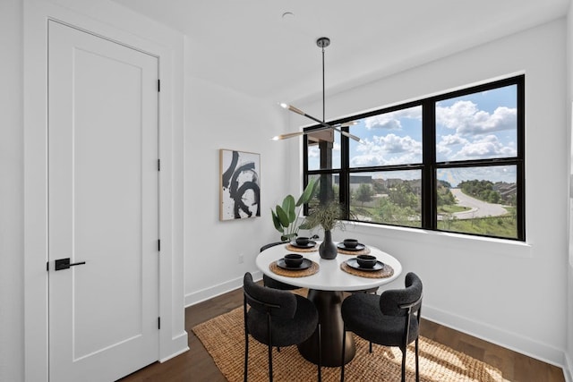 dining area featuring a notable chandelier, plenty of natural light, and dark wood-type flooring