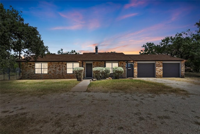 single story home featuring a garage, stone siding, driveway, and a front lawn